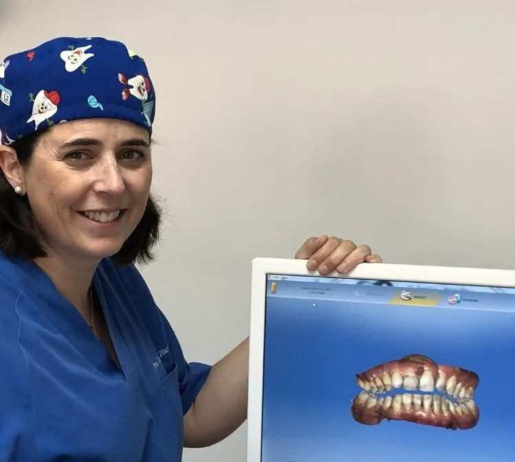 La Dra. Carmen Iturbe Zabala sonriendo junto a una pantalla que muestra un modelo digital de los dientes